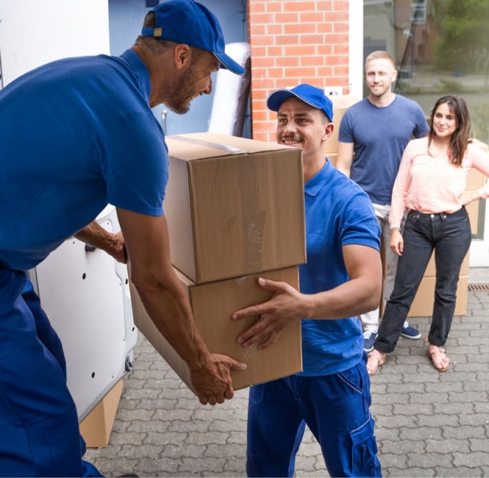 Two crew members carrying wrapped furniture